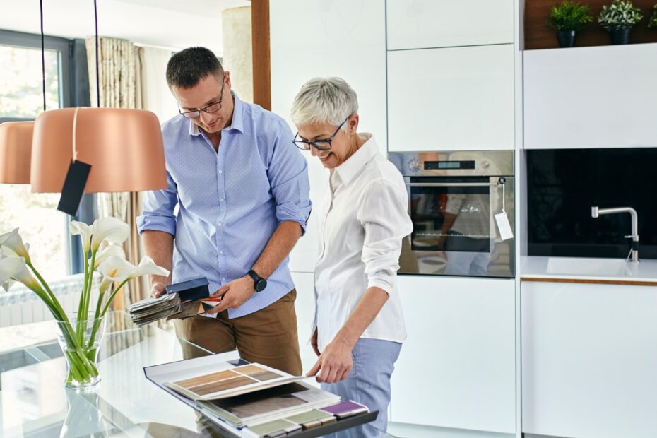 Un especialista en cocinas y una especialista en interiorismo miran muestras en una cocina de alta gama.